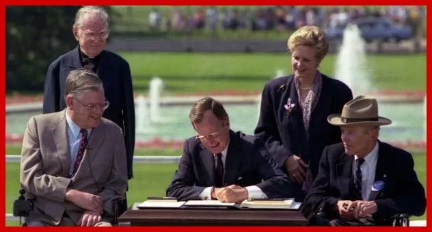 President George H.W. Bush signs the Americans with Disabilities Act on July 26, 1990. Standing left to right: Rev. Harold Wilkie; and Sandra Parrino, National Council on Disability; Seated left to right: Evan Kemp, Equal Employment Opportunity Commission
