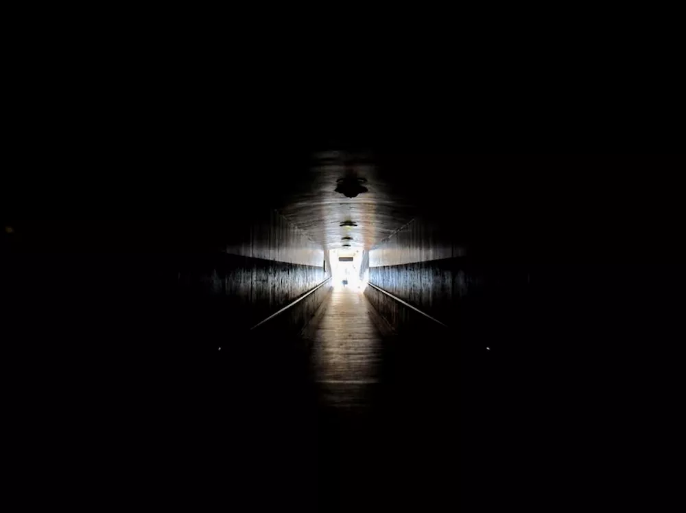 A daylight glow bursting like a star at the end of the ramped tunnel taken from a wheelchair perspective.