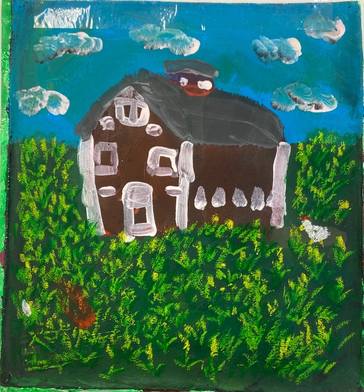 A brown farmhouse sits in a grassy field under a blue sky with clouds, with a white chicken near the house.