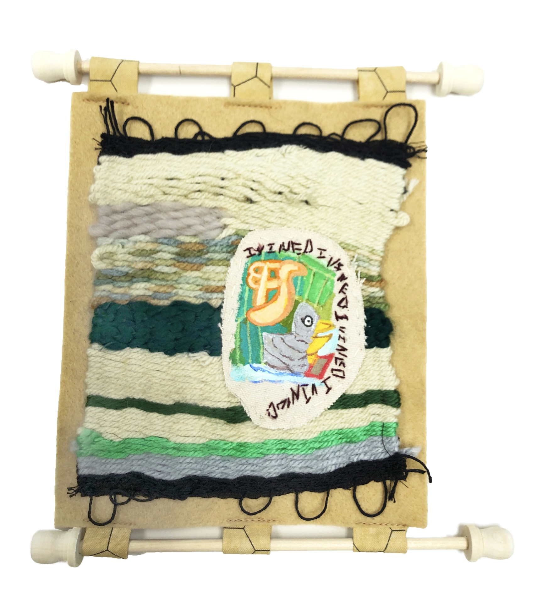 A photograph of weaving on beige felt. The weaving comprises stripes of various yarns, including whites, greens, grays, and black. A pelican reading a book is painted on a sewn on leather patch.