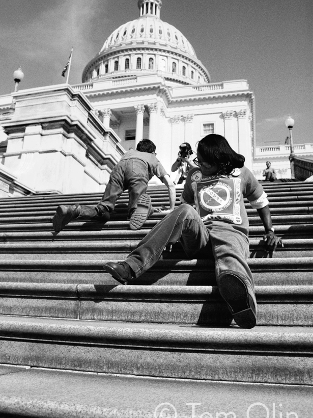 A powerful moment from the Capitol Crawl shows two disability rights activists climbing the steps of the U.S. Capitol using only their hands and legs, protesting the lack of accessible entrances in 1990.